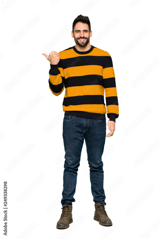 Full-length shot of Handsome man with striped sweater pointing to the side to present a product on isolated white background Full-length shot of Handsome man with striped sweater pointing to the side to present a product on isolated white background