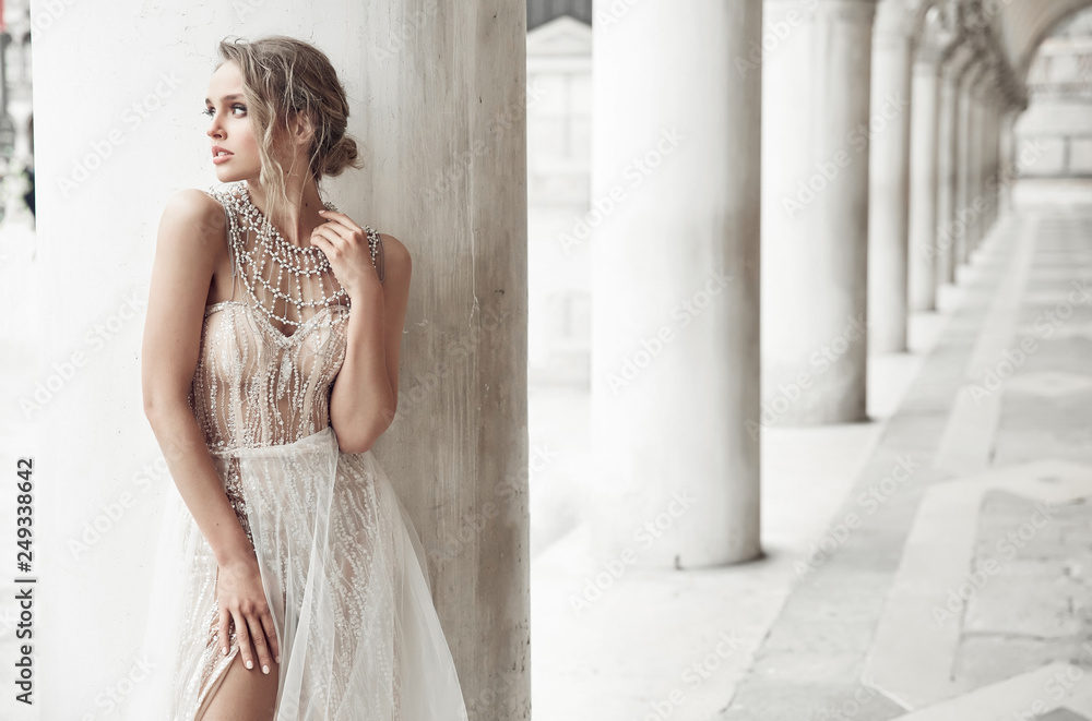 Beautiful bride in long elegant, luxury ivory dress and messy updo hairstyle, posing near columns in Venice, Italy Beautiful bride in long elegant, luxury ivory dress and messy updo hairstyle, posing near columns in Venice, Italy