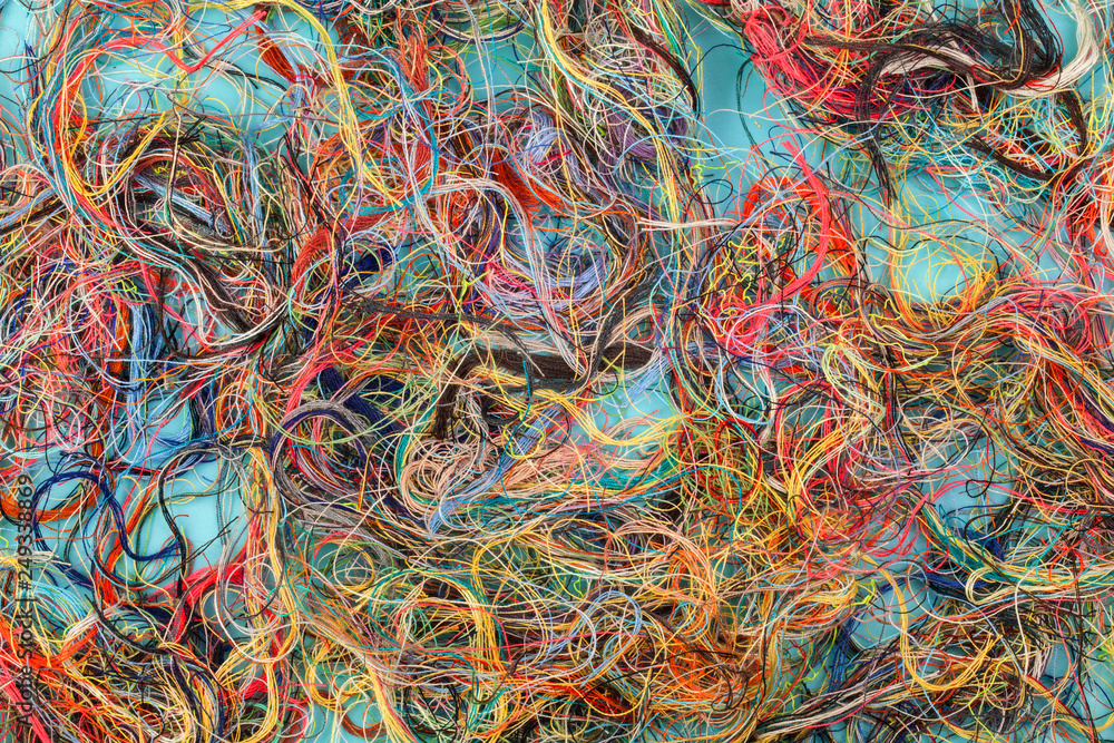Colorful tangled threads on blue background. Closeup.