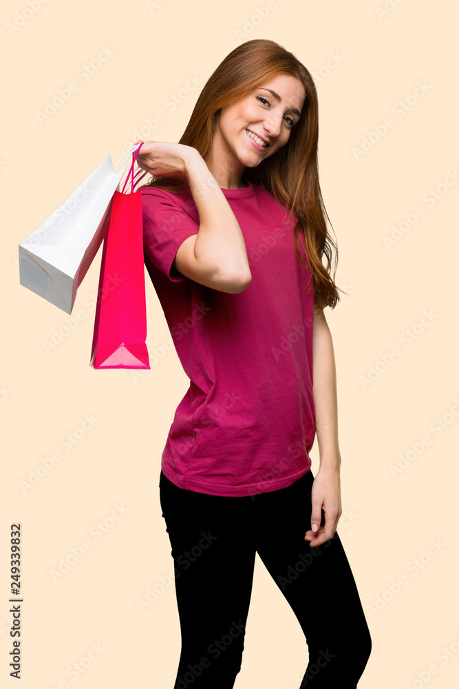 Young redhead girl holding a lot of shopping bags on isolated yellow background Young redhead girl holding a lot of shopping bags on isolated yellow background