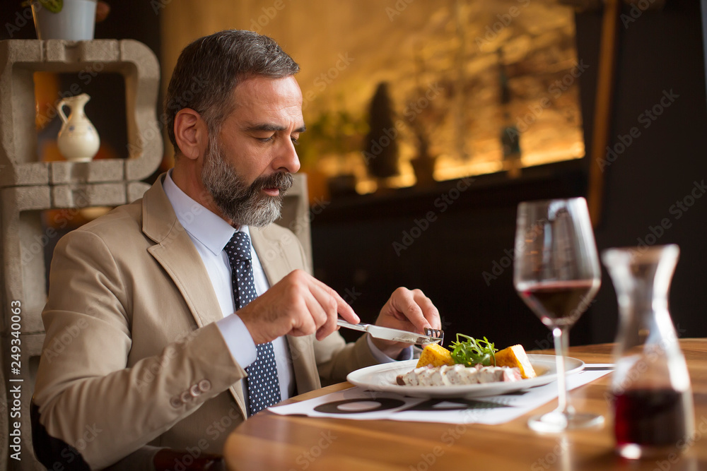 Handsome senior man eating lunch in restaurant