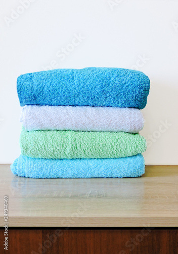 Stack of colorful bath towels  on white background.Pile of rainbow colored towels isolated.Top view.Hygiene, fabric,spa and textile concept.