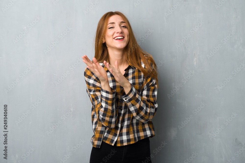 Young redhead girl over grunge wall applauding after presentation in a conference Young redhead girl over grunge wall applauding after presentation in a conference