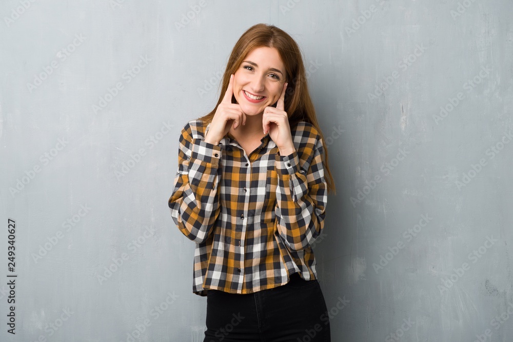 Young redhead girl over grunge wall smiling with a happy and pleasant expression Young redhead girl over grunge wall smiling with a happy and pleasant expression