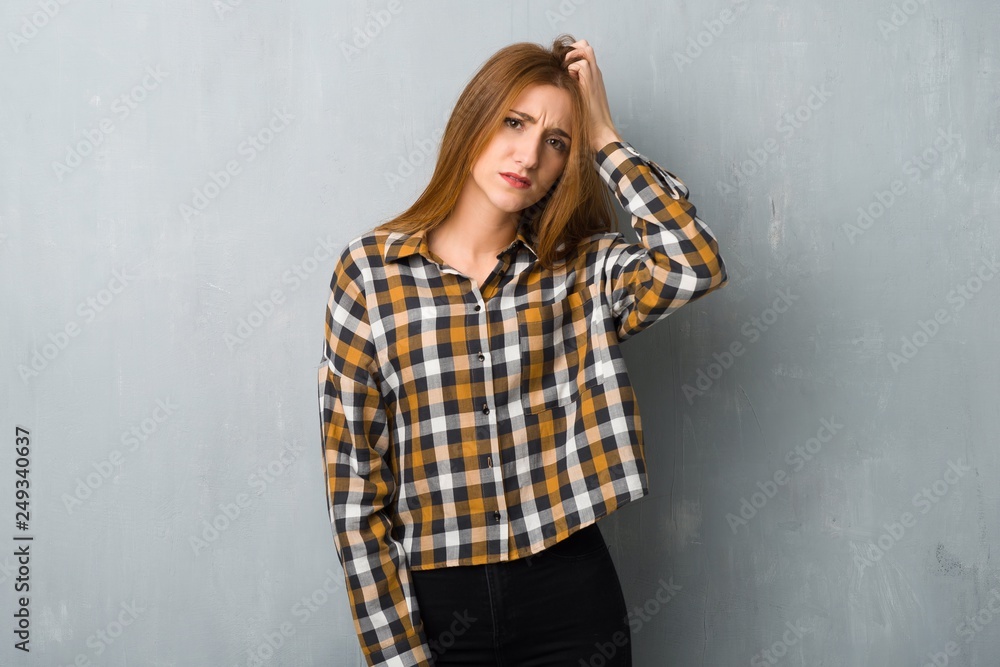 Young redhead girl over grunge wall with an expression of frustration and not understanding Young redhead girl over grunge wall with an expression of frustration and not understanding