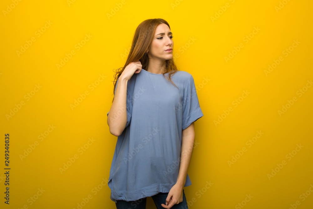 Young redhead girl over yellow wall background with tired and sick expression Young redhead girl over yellow wall background with tired and sick expression