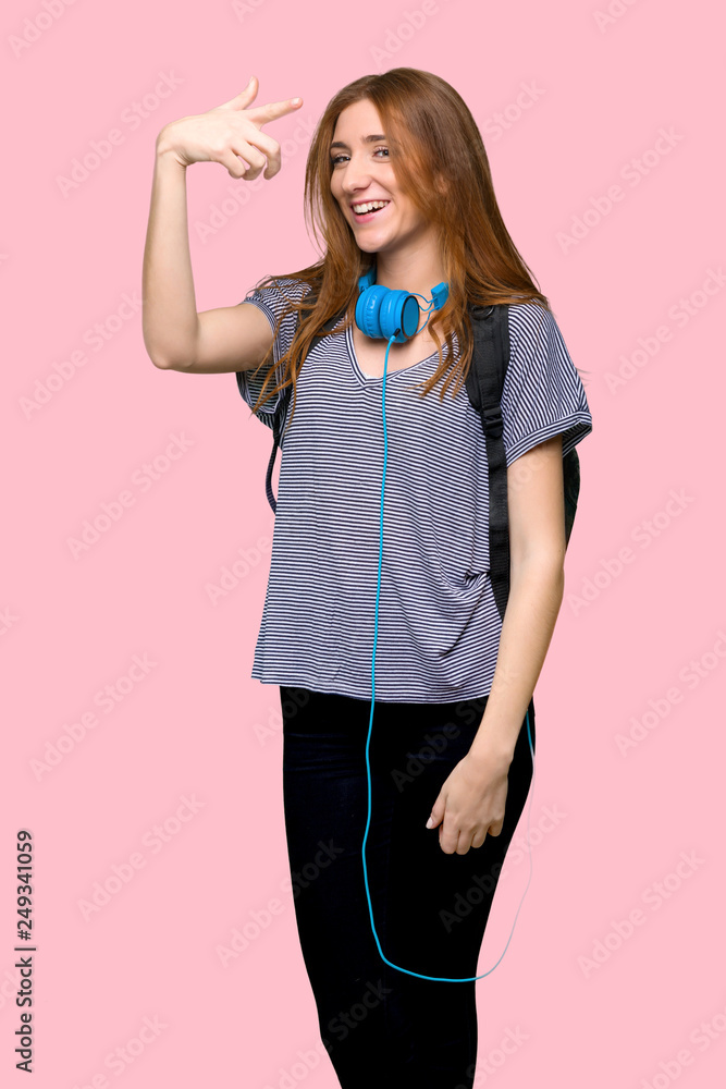 Redhead student woman frustrated by a bad situation and pointing to the front on isolated pink background Redhead student woman frustrated by a bad situation and pointing to the front on isolated pink background