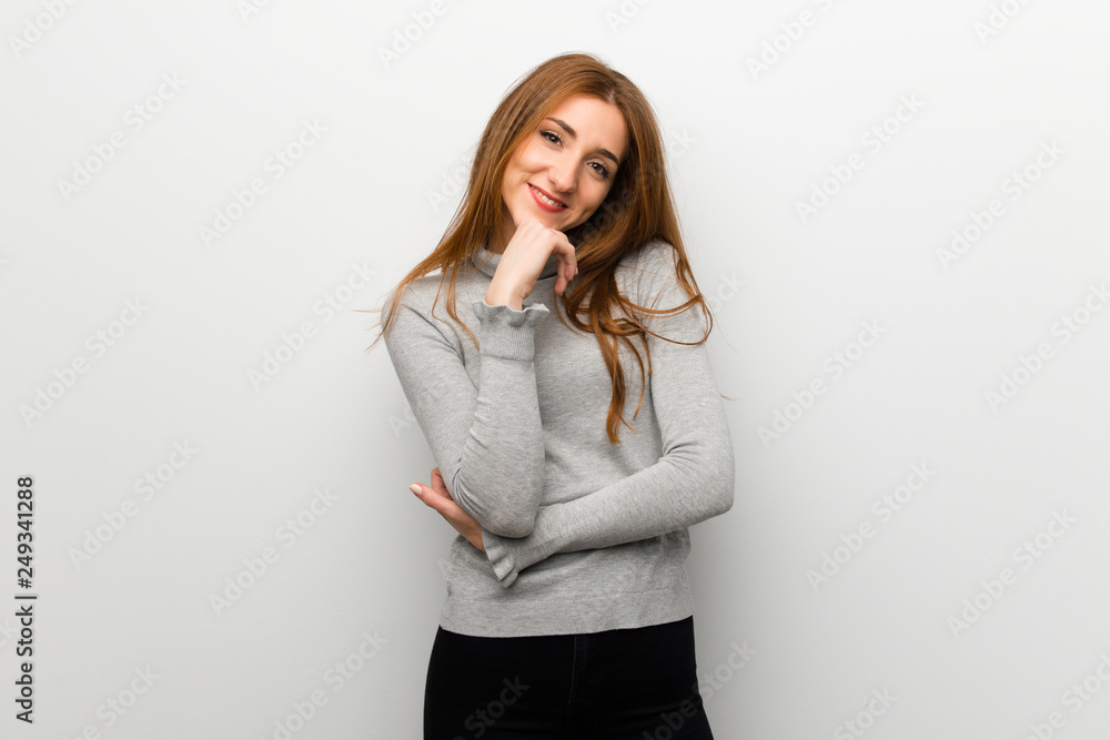 Redhead girl over white wall smiling and looking to the front with confident face Redhead girl over white wall smiling and looking to the front with confident face