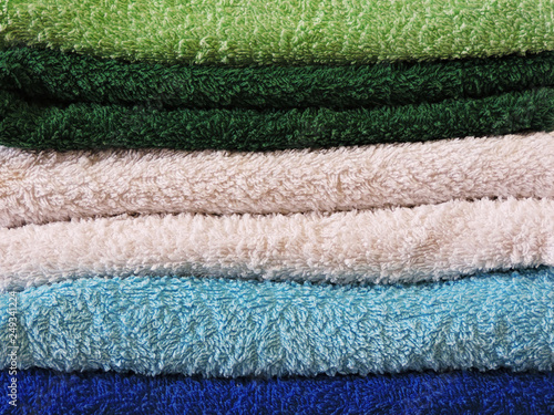Stack of colorful bath towels  on white background.Pile of rainbow colored towels isolated.Top view.Hygiene, fabric,spa and textile concept.