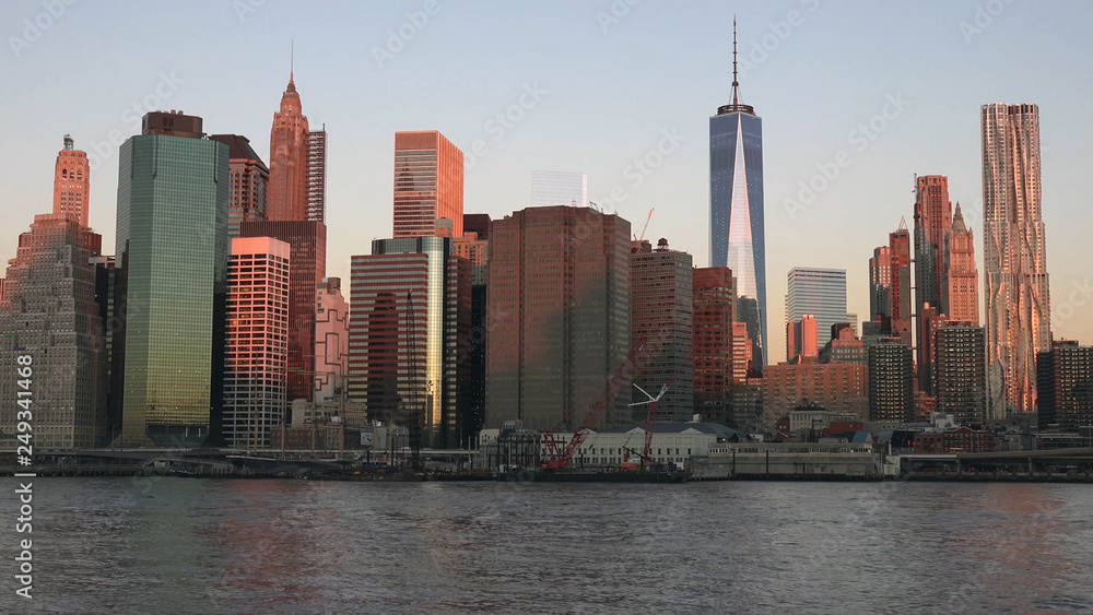 Fototapeta premium East river and Manhattan skyline with view of urban skyscrapers at sunrise