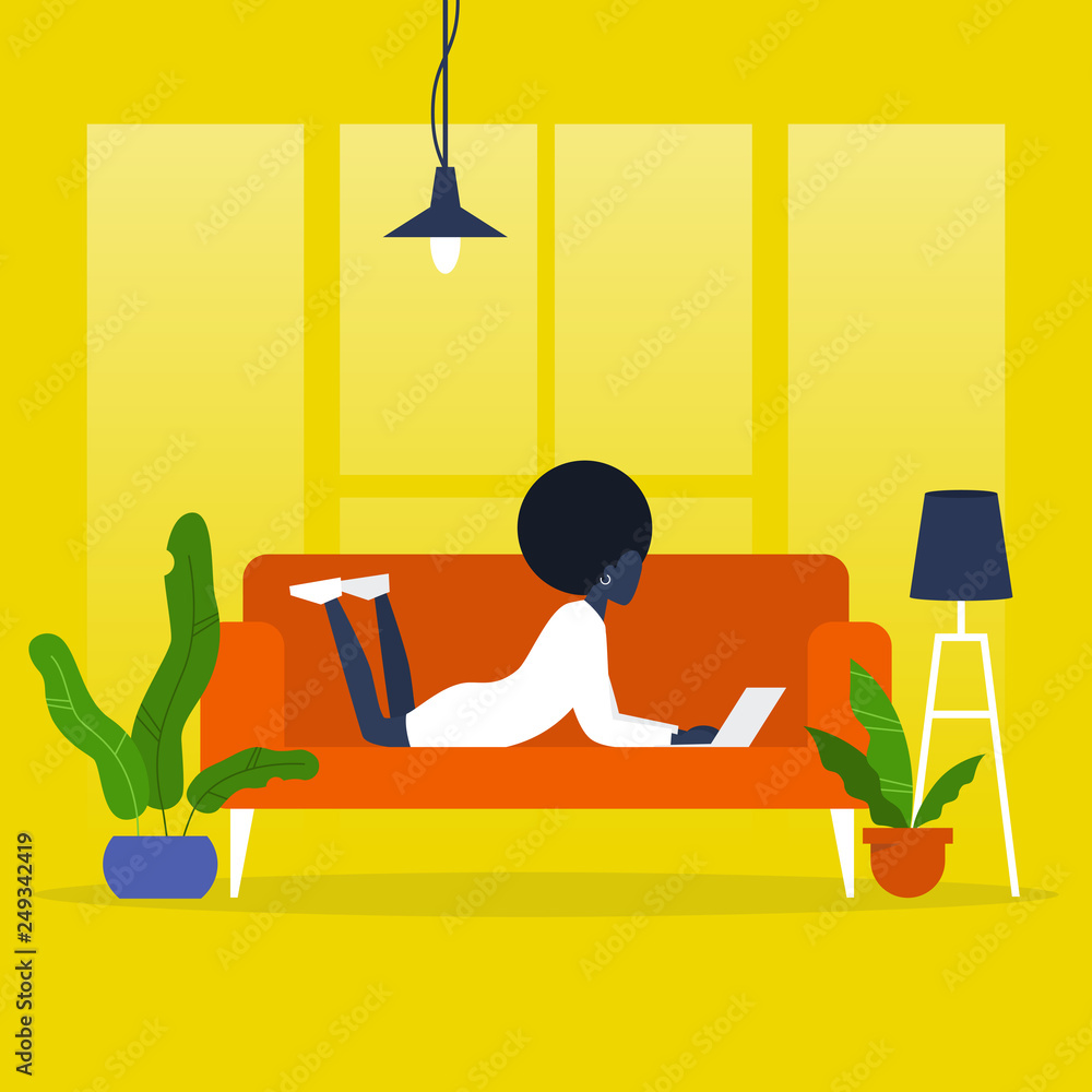 Fototapeta premium Young black female manager lying on a sofa with a laptop