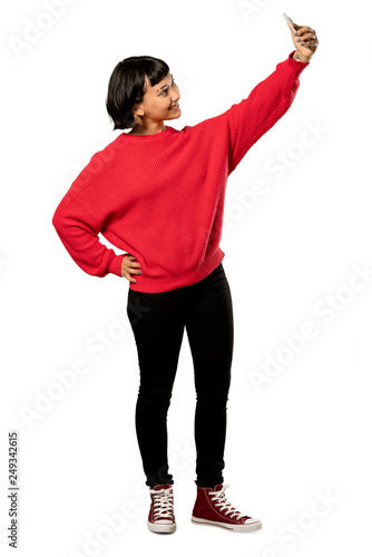 A full-length shot of a Short hair girl with red sweater making a selfie over isolated white background