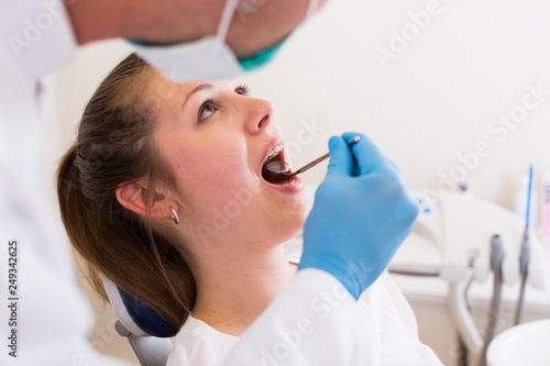 Young doctor in white is taking examination of a woman on the chair