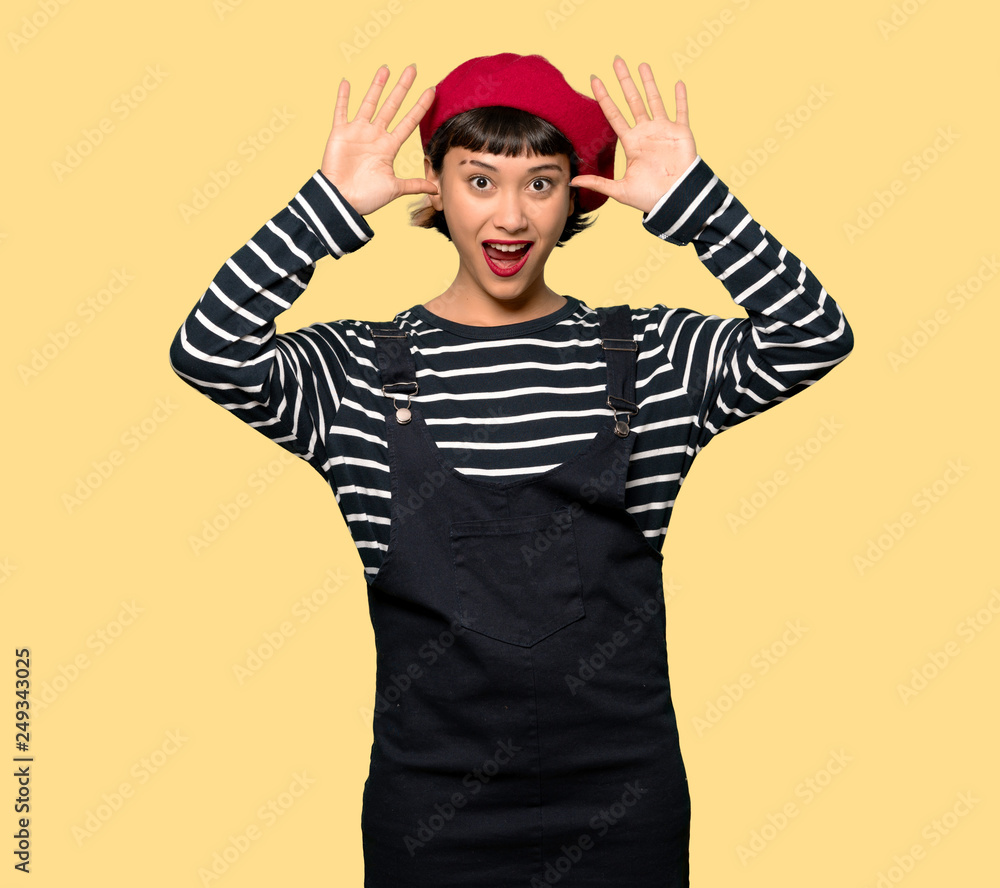 Young woman with beret with surprise and shocked facial expression over yellow background Young woman with beret with surprise and shocked facial expression over yellow background