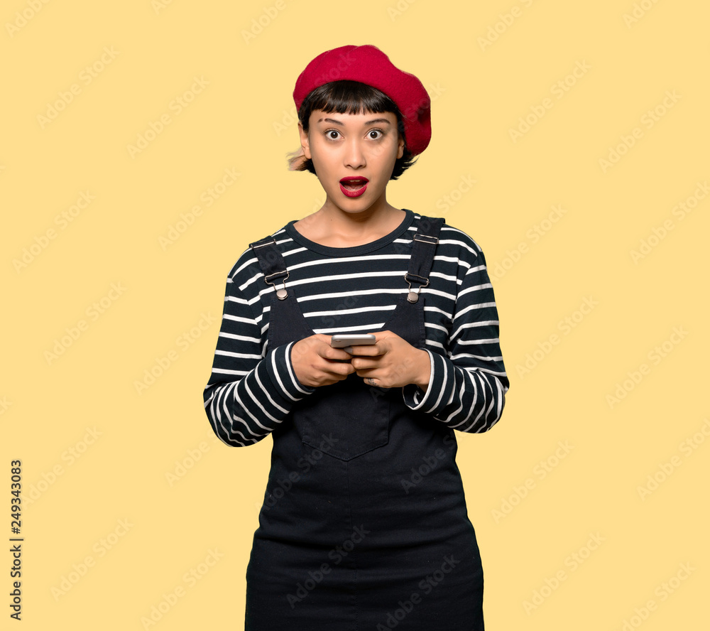 Young woman with beret surprised and sending a message Young woman with beret surprised and sending a message