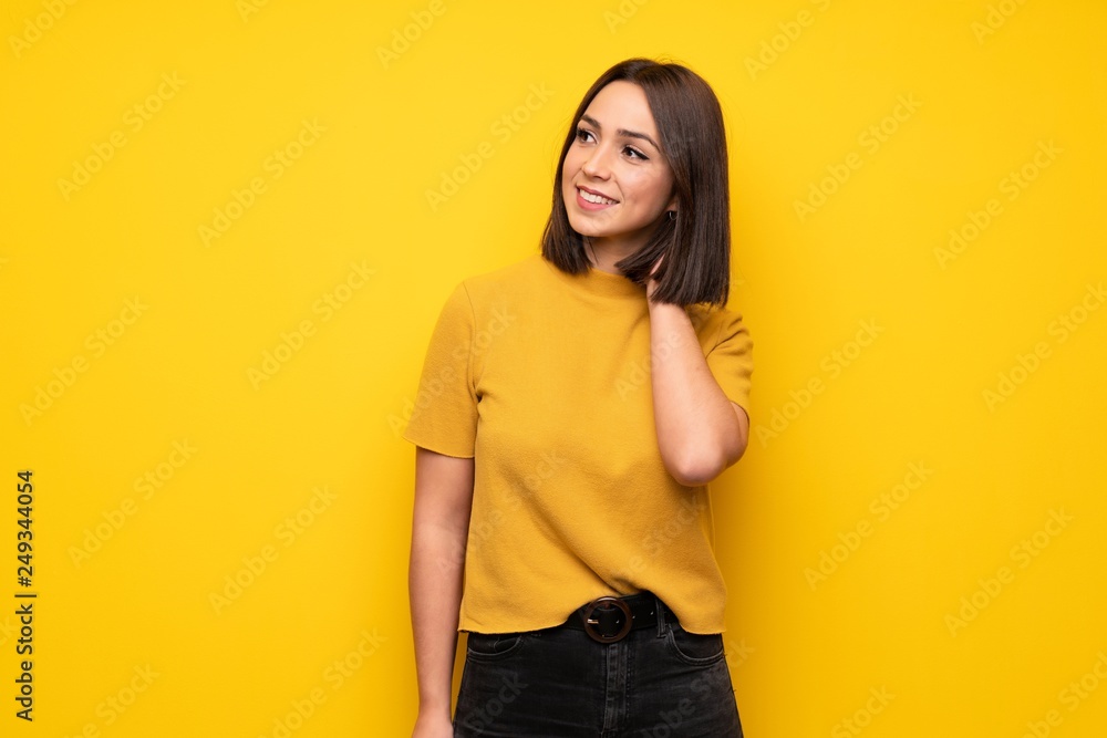 Young woman over yellow wall thinking an idea while scratching head Young woman over yellow wall thinking an idea while scratching head