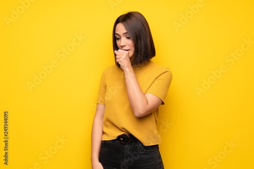 Young woman over yellow wall is suffering with cough and feeling bad