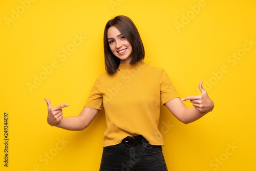 Young woman over yellow wall proud and self-satisfied