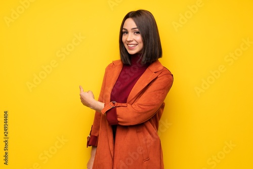 Young woman with coat pointing back © luismolinero