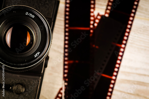 The concept of analog photography, the camera on the background of scattered negatives