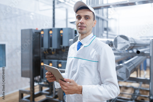 man in a white robe with a tablet in his hands is in the production shop at the factory © Ivan Traimak