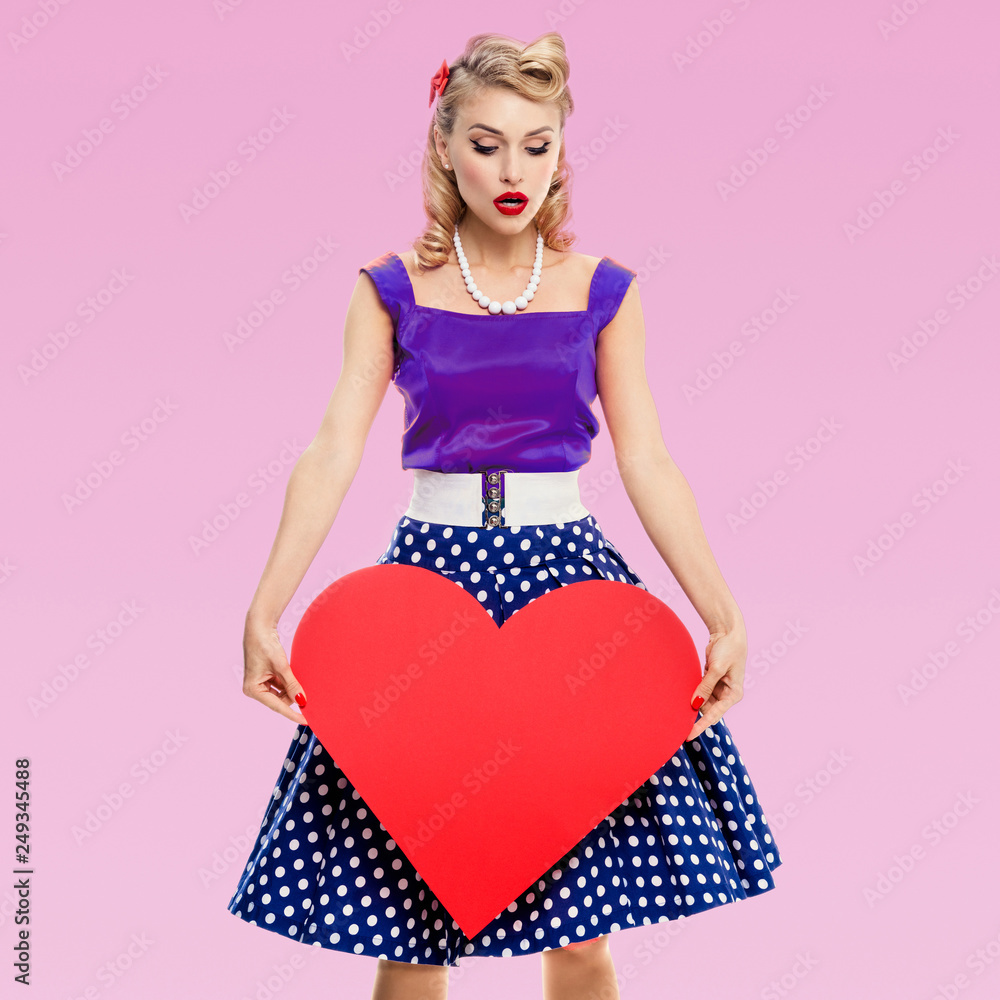 smiling woman holding heart symbol, dressed in pin-up style smiling woman holding heart symbol, dressed in pin-up style