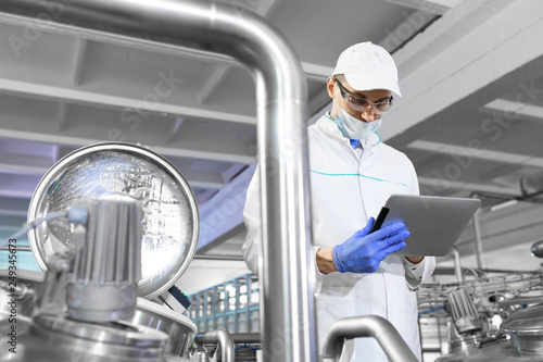 Technologist stands with a tablet in the shop at the dairy Plant photo