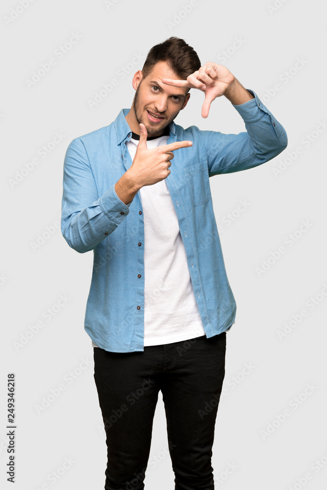 Handsome man focusing face. Framing symbol over grey background Handsome man focusing face. Framing symbol over grey background