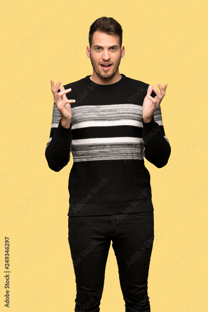 Handsome man with shocked facial expression over yellow background Handsome man with shocked facial expression over yellow background