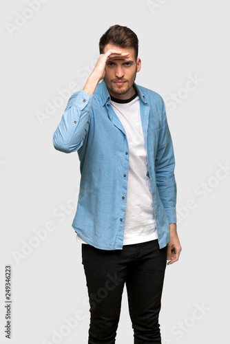 Handsome man looking far away with hand to look something over grey background © luismolinero