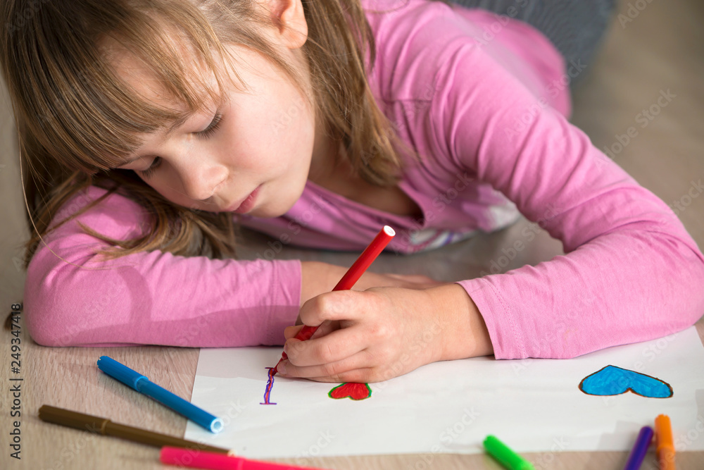 Child girl drawing with colorful pencils crayons heart on white paper. Art education, creativity concept. Child girl drawing with colorful pencils crayons heart on white paper. Art education, creativity concept.