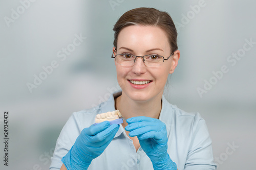Zahnersatz wird im Zahnlabor farblich von Dentaltechnikerin überprüft photo