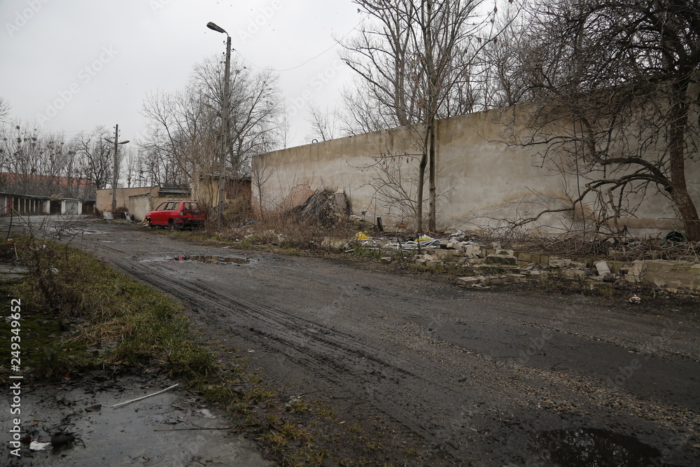 Old, neglected, ruined garages. Muddy, holey, uneven road with puddles. Winter, autumn landscape in the city. Wrocław, Wroclaw, Breslau. Lower Silesia, Dolny Śląsk. Polska, Poland, Polen