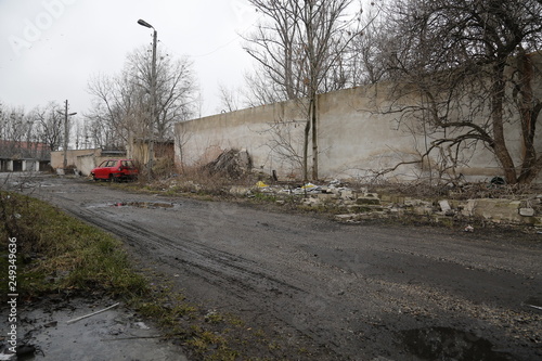 Old, neglected, ruined garages. Muddy, holey, uneven road with puddles. Winter, autumn landscape in the city. Wrocław, Wroclaw, Breslau. Lower Silesia, Dolny Śląsk. Polska, Poland, Polen photo