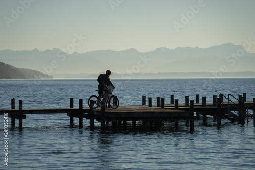 Radfahrer auf dem Steg am Starnberger See bei Sonnenuntergang