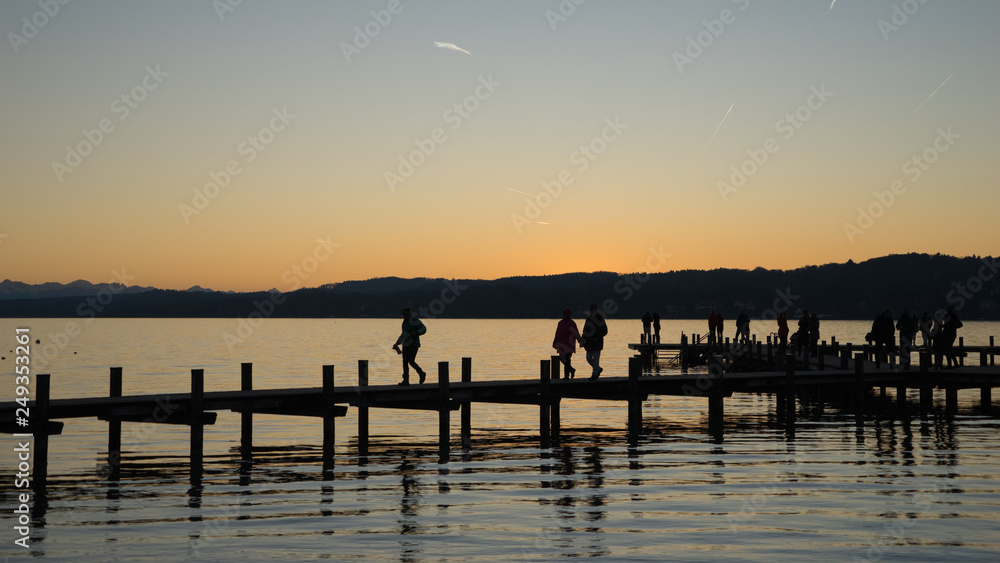 Menschen auf dem Steg am Starnberger See bei Sonnenuntergang
