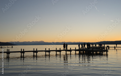 Menschen auf dem Steg am Starnberger See bei Sonnenuntergang