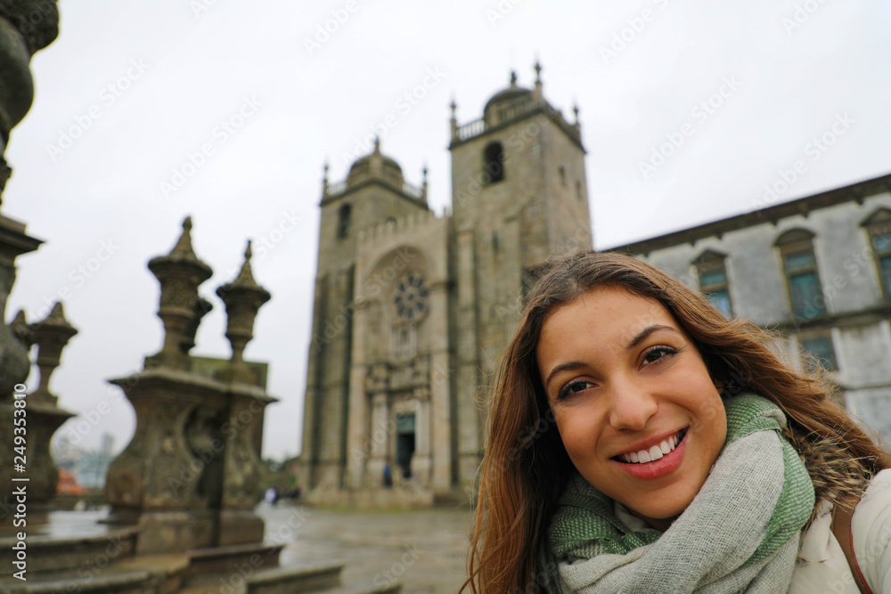 Happy young woman take selfie photo in front of Porto Cathedral in winter time. Self portrait of beautiful girl in Porto, Portugal.