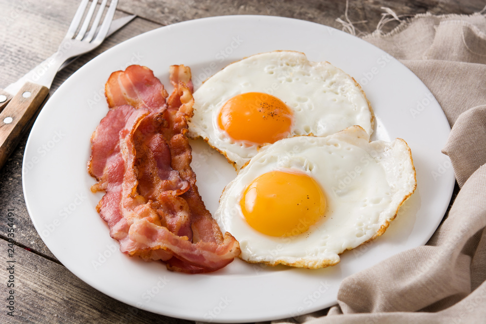 Fried eggs and bacon for breakfast on wooden table. Close up Fried eggs and bacon for breakfast on wooden table. Close up