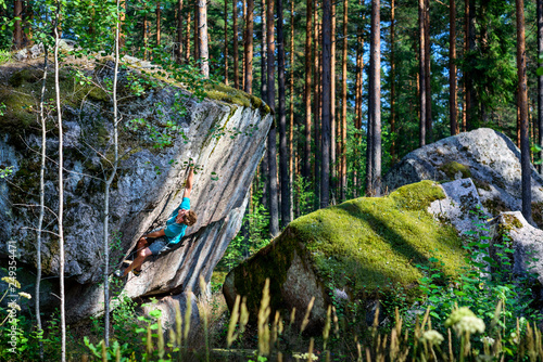 Rock climber ascending a challenging boulder. Sport and active life concept. photo