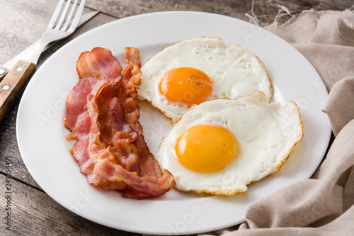 Fried eggs and bacon for breakfast on wooden table. Close up