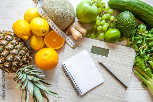 Flat lay composition with scales, healthy vegetables and fruit on wooden background. Weight loss diet