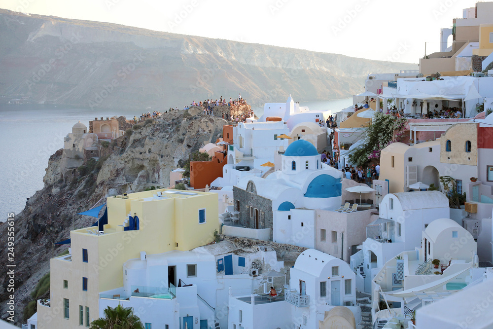 SANTORINI, GREECE - JULY 19, 2018: picturesque village of Oia with tourists for the sunset show, Santorini island, Greece SANTORINI, GREECE - JULY 19, 2018: picturesque village of Oia with tourists for the sunset show, Santorini island, Greece