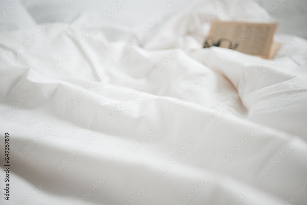 selective focus of book and glasses on white empty bed selective focus of book and glasses on white empty bed
