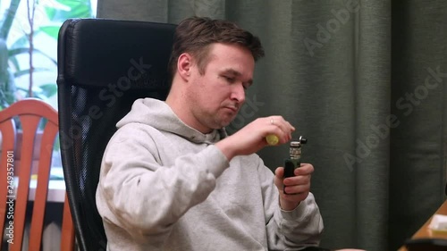 man smokes an electronic cigarette in his house