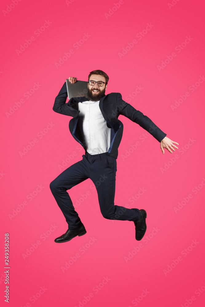 Jumping man in suit holding laptop