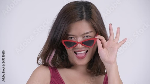 Wallpaper Mural Face of young happy Asian tourist woman peeking over sunglasses Torontodigital.ca