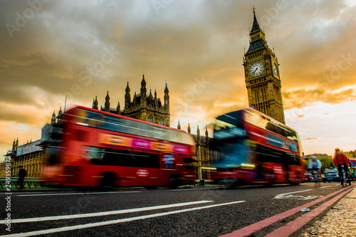 Two red buses drives over the Westminister Bridge. In the background the Big Ben. photo