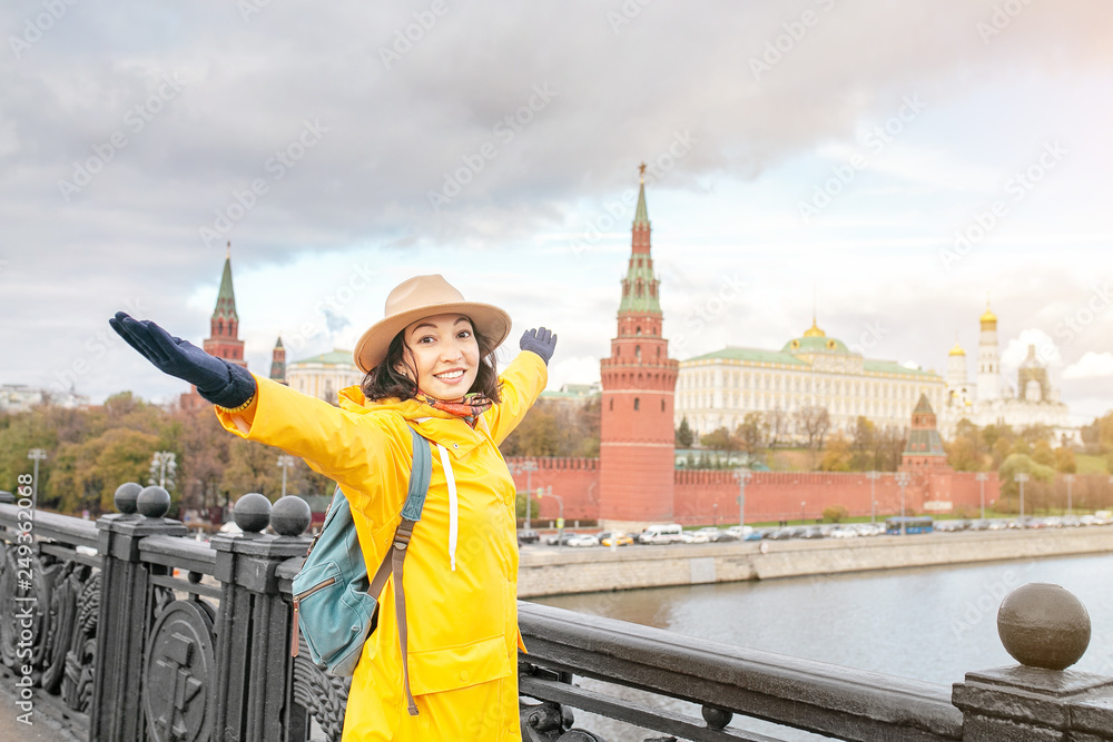 Obraz premium Happy asian woman tourist on the background of the Kremlin wall tower from the Moscow river embankment. Travel in Russia concept