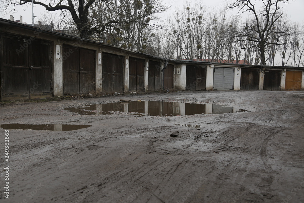 Old, neglected, ruined garages. Muddy, holey, uneven road with puddles. Winter, autumn landscape in the city. Wrocław, Wroclaw, Breslau. Lower Silesia, Dolny Śląsk. Polska, Poland, Polen Old, neglected, ruined garages. Muddy, holey, uneven road with puddles. Winter, autumn landscape in the city. Wrocław, Wroclaw, Breslau. Lower Silesia, Dolny Śląsk. Polska, Poland, Polen